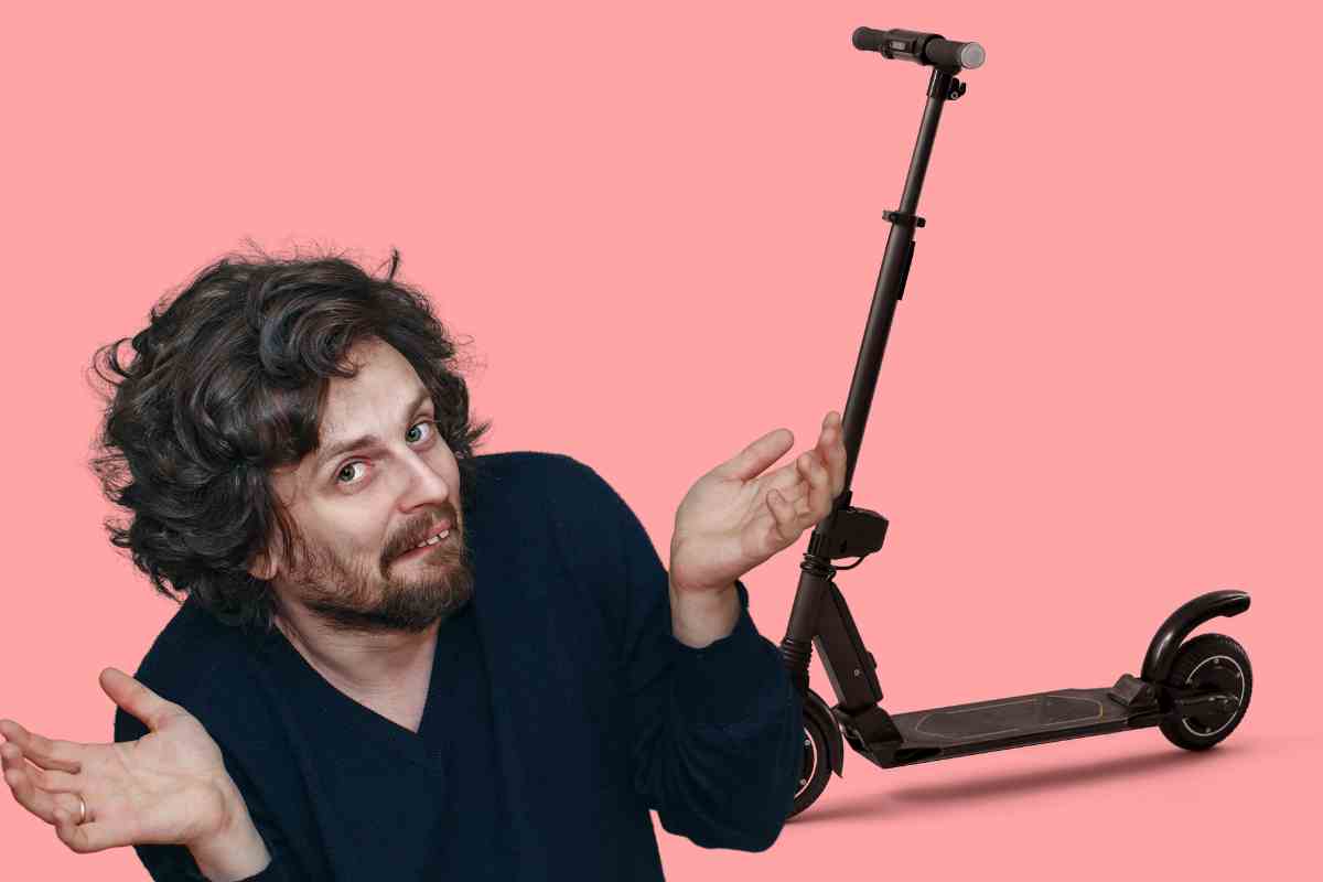 Uomo con la braccia larghe e alle spalle un monopattino